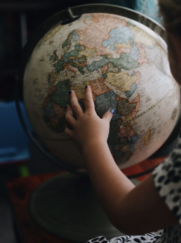 girls hand on a map globe